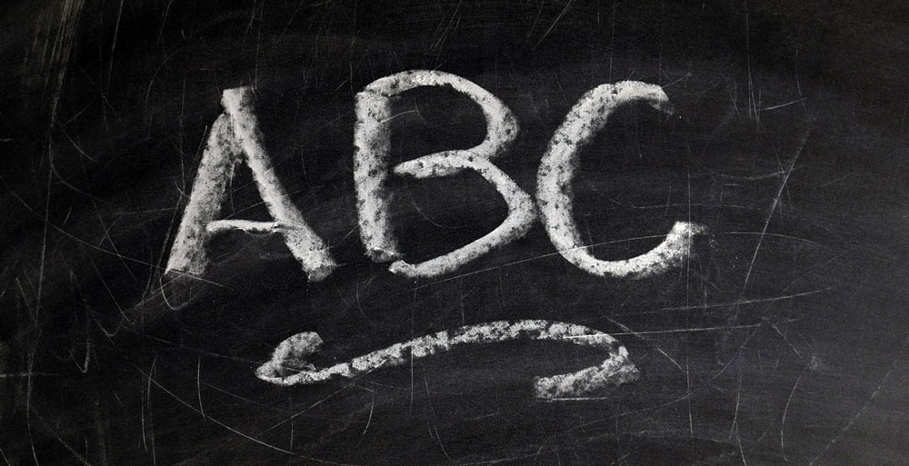 the letters a b c written in chalk on a blackboard